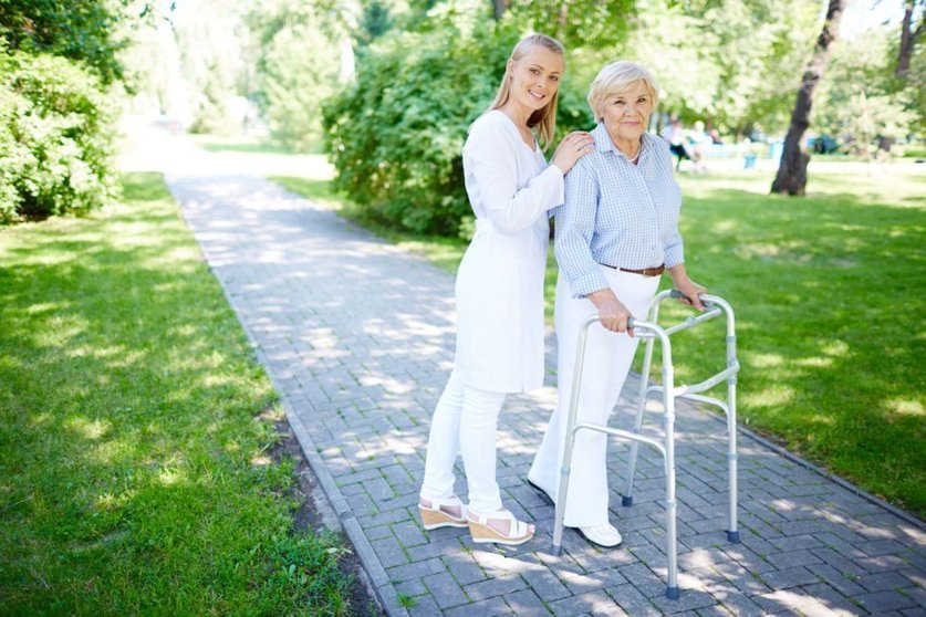 Pretty carer walking out with senior patient